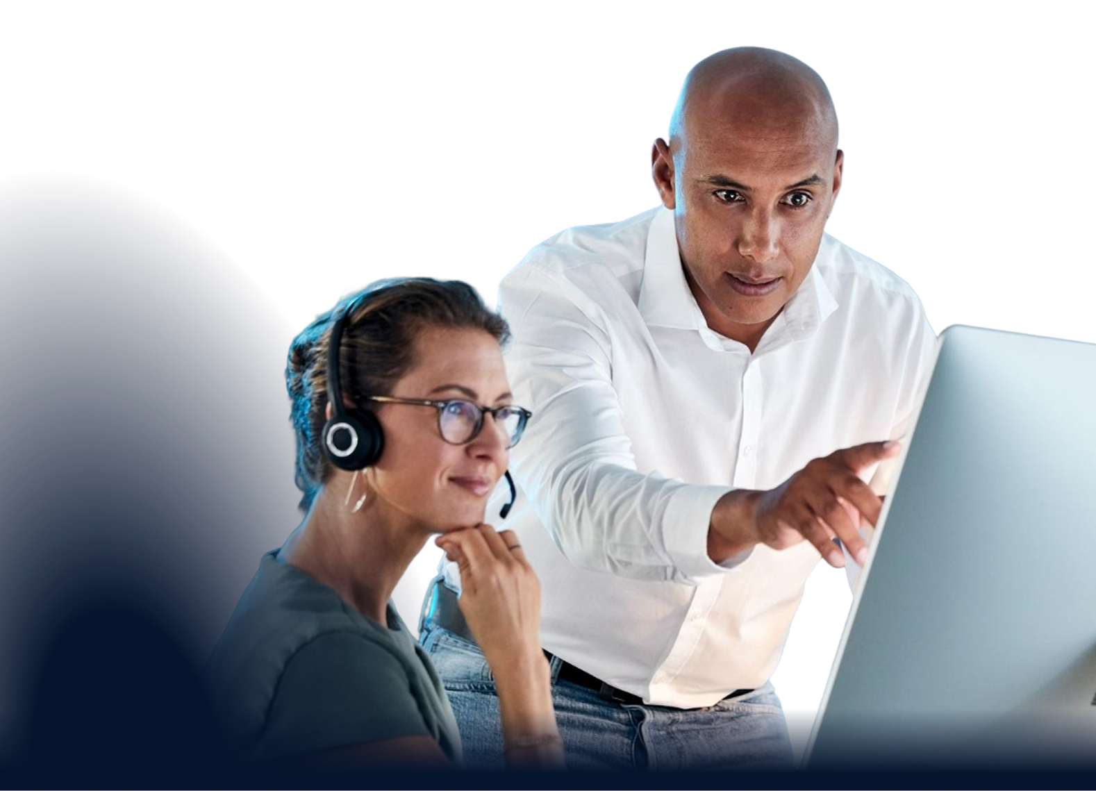 Help desk technician wearing a headset while a colleague points at a laptop screen